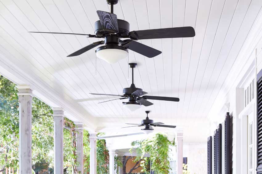 three traditional outdoor ceiling fans hung from a covered patio 