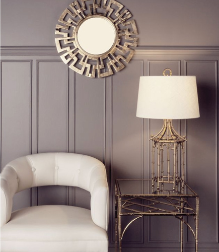 Gold mirror hanging over chair with a smart table lamp on a side table.