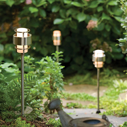 three silver low voltage pathway lights installed next to an outdoor walkway