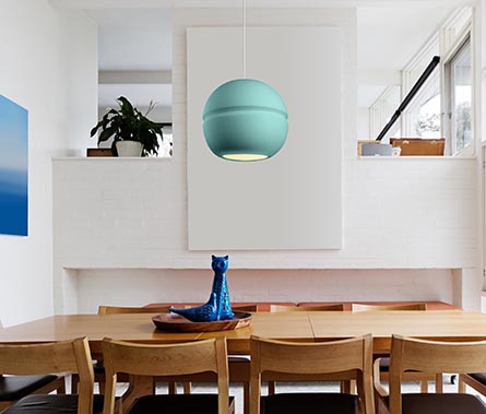 green circular ceramic pendant light hanging over wooden dining table 