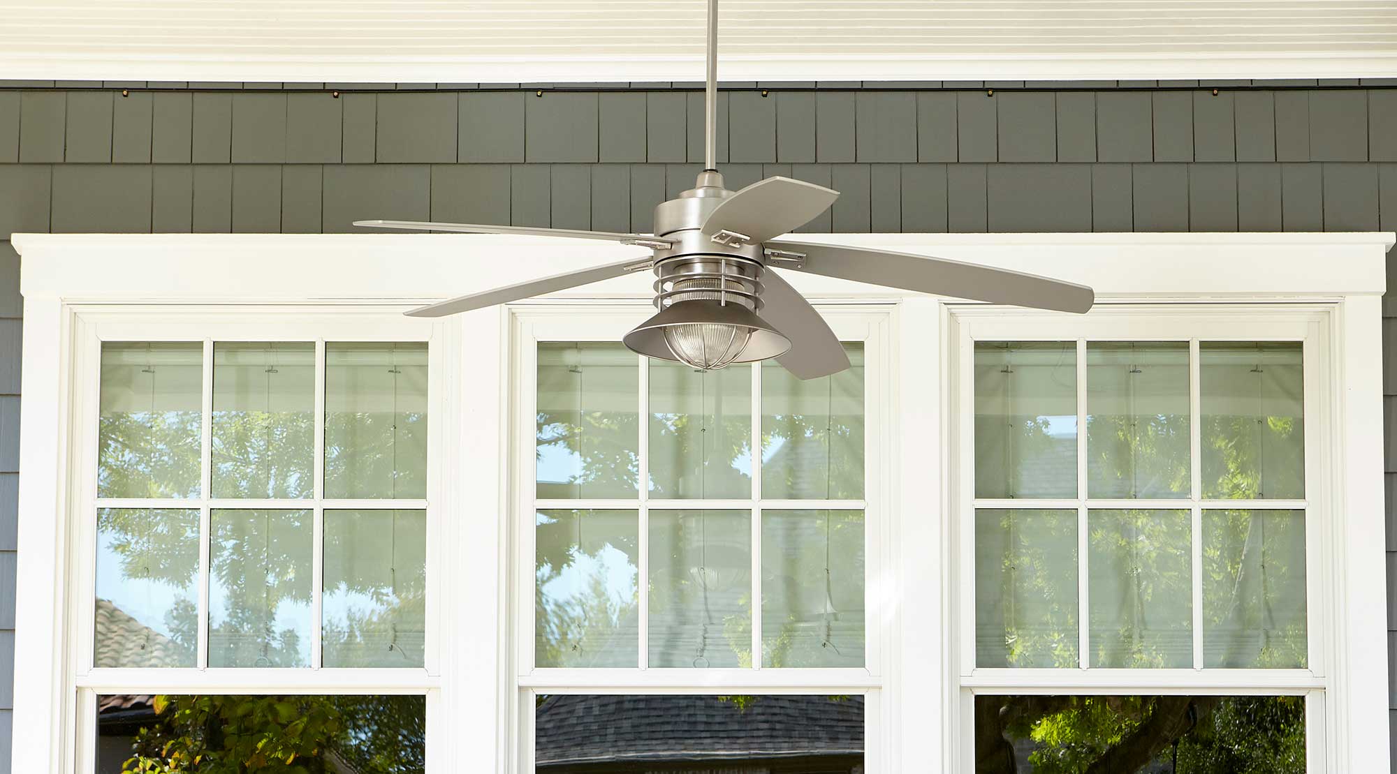 one outdoor ceiling fan on front porch hanging above white chairs 