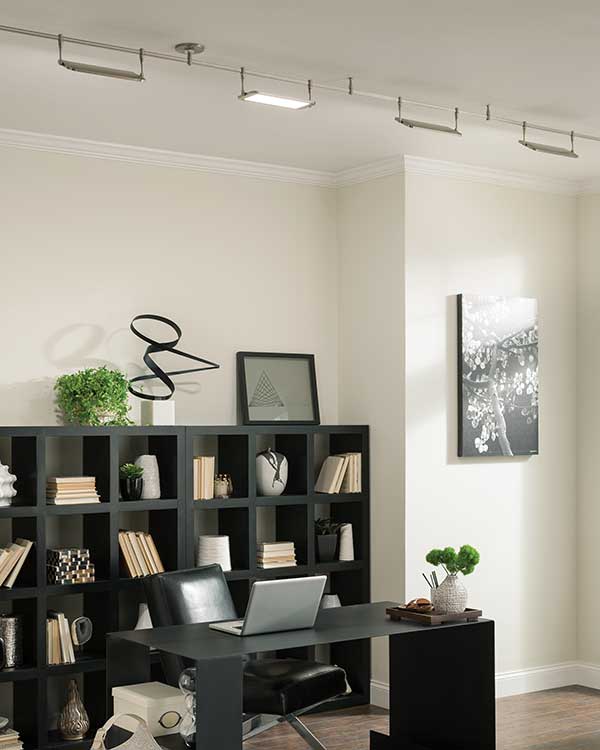 monorail track lighting system hung above black wooden desk