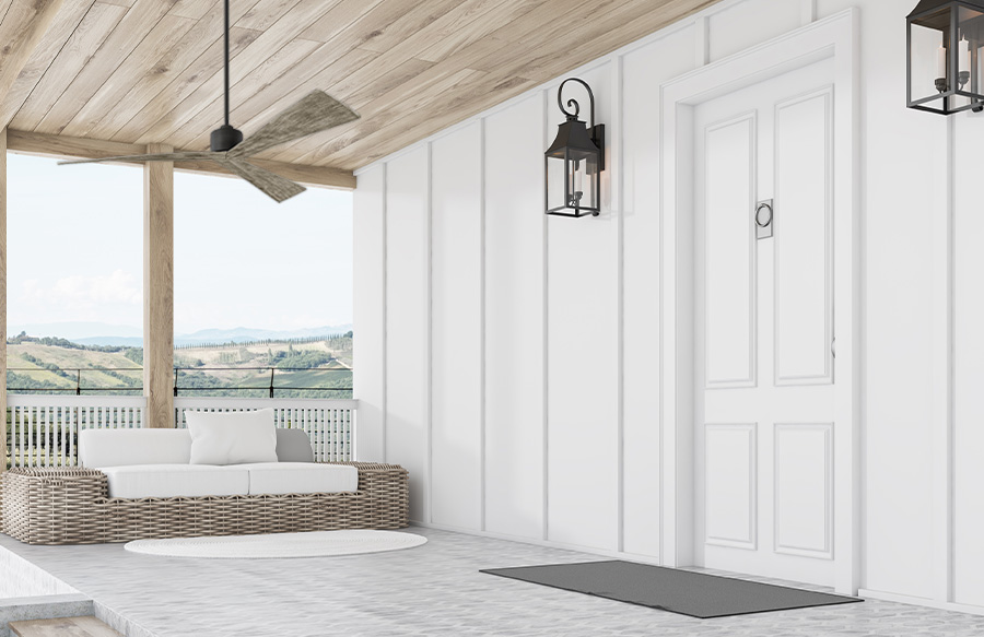 White front porch in a mountainous setting with wicker couch and natural wood ceiling and Visual Comfort Fan Collection Adler modern aged pewter outdoor ceiling fan with light grey weathered oak blades