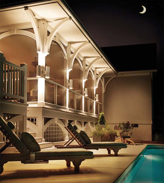 white cylinder outdoor wall lights in a pool setting at night
