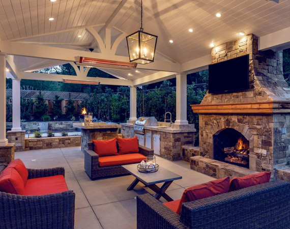 infratech medium wave heater heating an outedoor living room with a stone fire place and outdoor tv